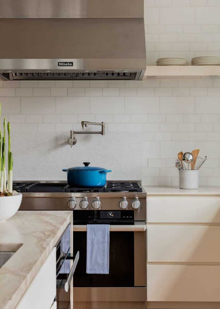 A pot filler above the professional style range and hood is another functional touch for serious cooking.
