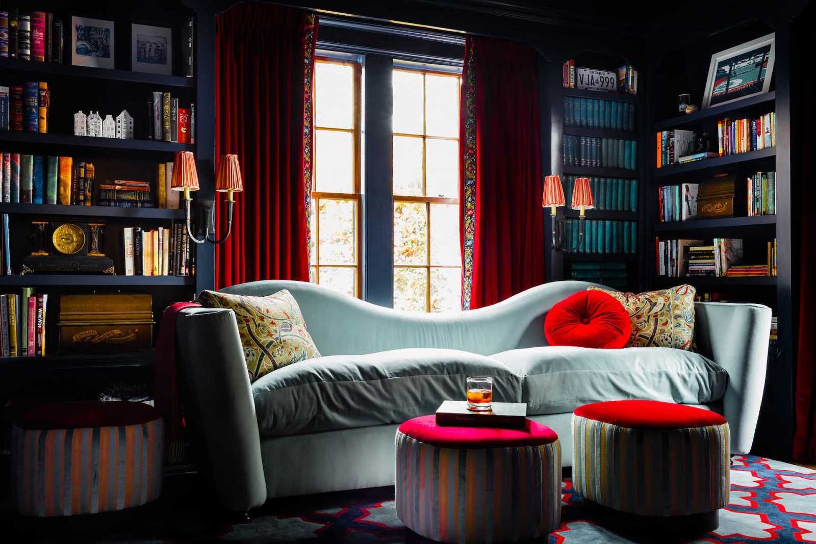 The library is painted a deep blue, and the red velvet curtains with a floral trim are a nod to the home's English Cottage style architecture.