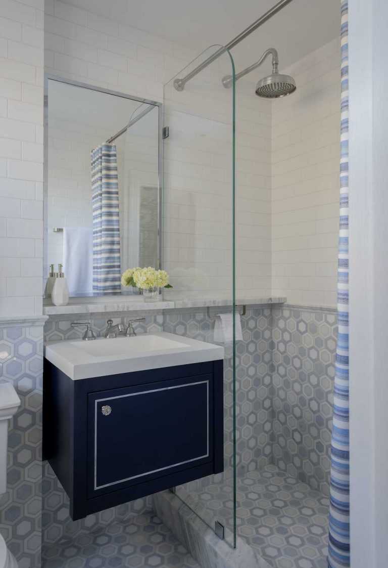 Guest bath has hexagonal marble mosaic tile on the floors and wainscot, and a carrara marble shelf extending into the shower.