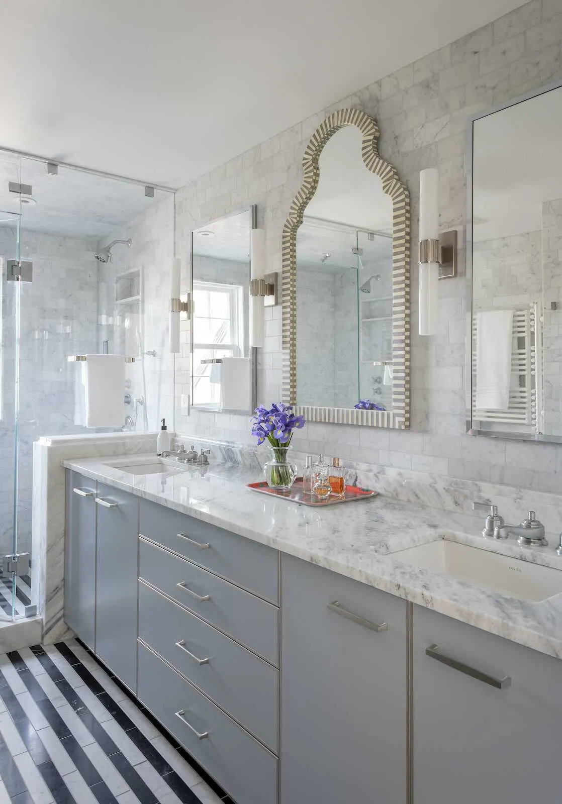 A custom vanity has a cararra marble countertop, two sinks and ample storage in the master bathroom.